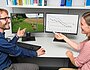 Mitarbeitende vor Bildschirmen mit Grafik